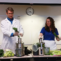 An image of a couple of employees giving a cooking demo at a corporate-sponsored event.