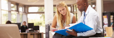 A banner of an image of a college guidance counselor reviewing documents with a young student.