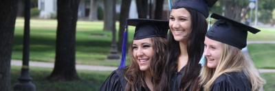 A banner of an image of a group of young, happy graduates posing in their graduation caps and gowns.