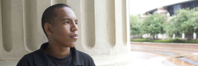 A banner of an image of a young man looking around campus.