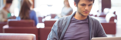 A banner of an image of a young man working at his laptop.
