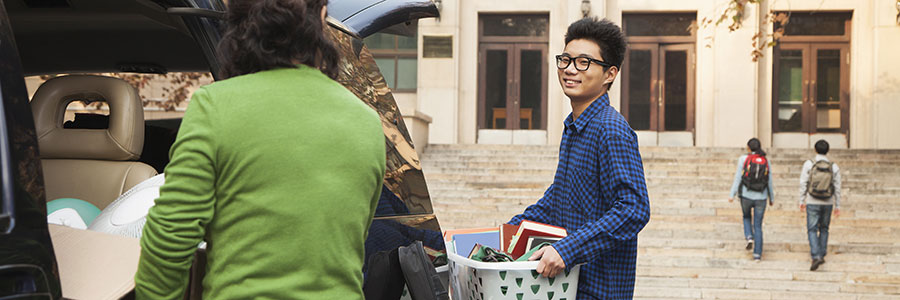 A banner of an image of a college student moving his belongings from his parents' car and into his new dormitory.