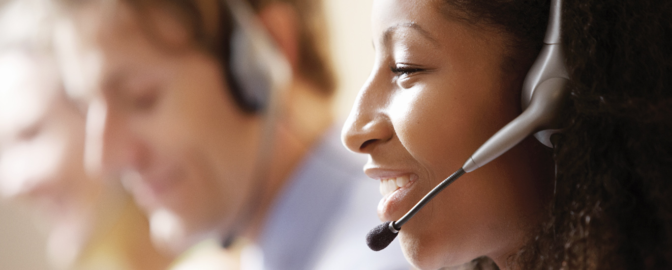 An image of a young woman with a headset talking to a customer.