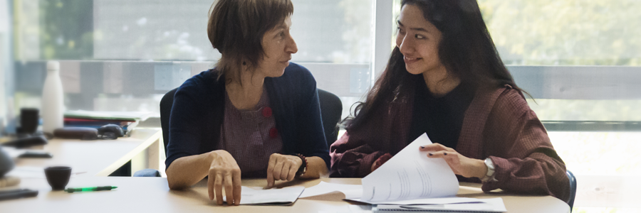 An image of a student looking over classwork with her professor.