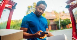 An image of a young man unloading boxes from the back of his car.